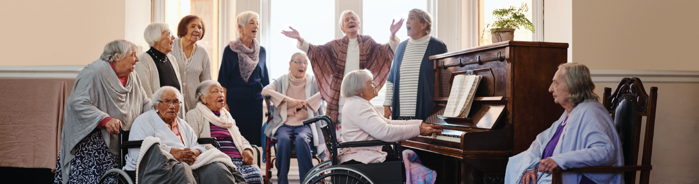 Older people gathered around piano singing